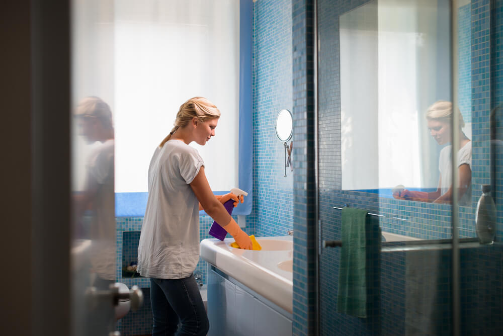 person cleaning the bathroom sink.